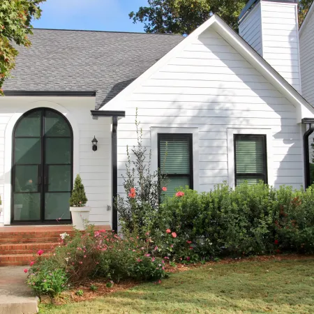White house with arched double front door with modern black frame and glass