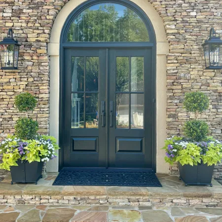 Stone house with black double French entry doors beneath arched transom