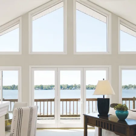 a room with a table and chairs and a window with a view of the ocean through the Infinity fiberglass custom fabricated windows in special shapes