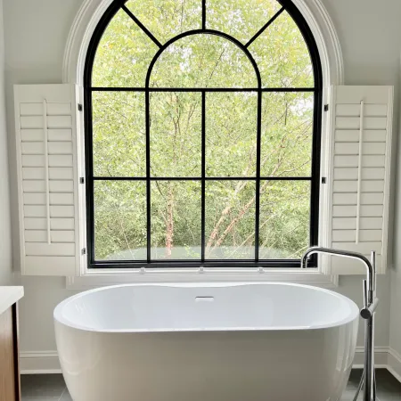 a bathtub in front of a large black round top window