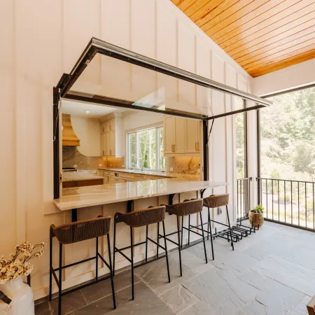 a kitchen with a large glass awning window opening onto the patio