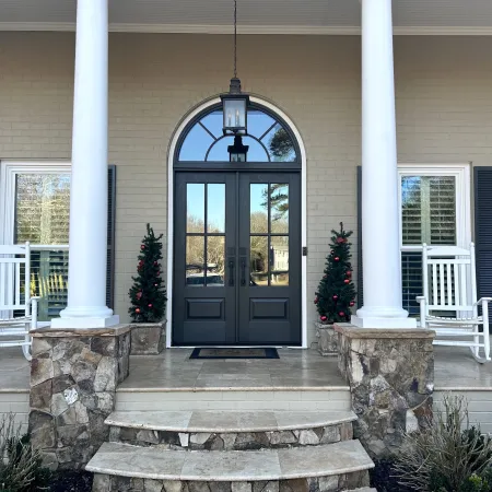 Front porch with white columns and black French front doors under arched transom