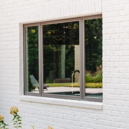 Exterior view of casement windows installed on a modern white brick home. 