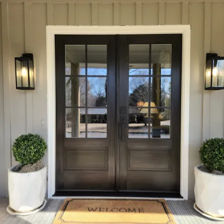 Front porch with double French entry doors in dark wood tone with glass.