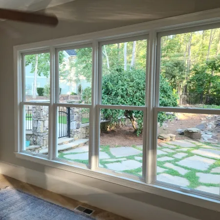 Interior view of 3 large double hung white Infinity from Marvin fiberglass windows overlooking the pavers and landscaping outside