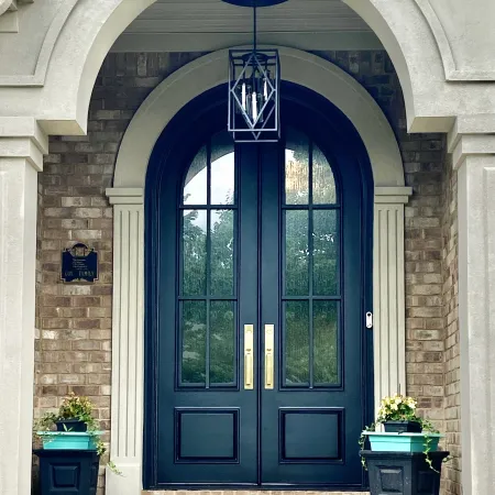 Arched black iron double front entry doors on brick house with arched entry detail
