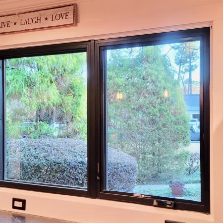 Kitchen window with a view of green bushes and trees, wall sign reading Live Laugh Love above the window.
