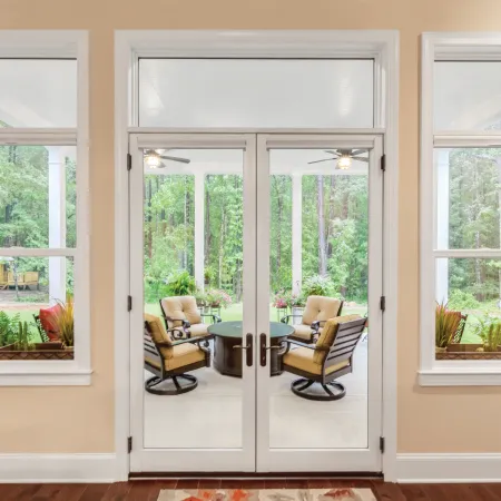 White fiberglass French doors leading to back patio with seating area