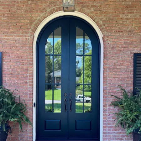 Black iron arched front door on brick house