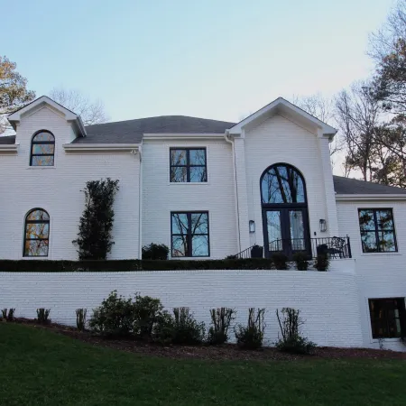 a white house with a lawn in front of it and several round top windows with black frames