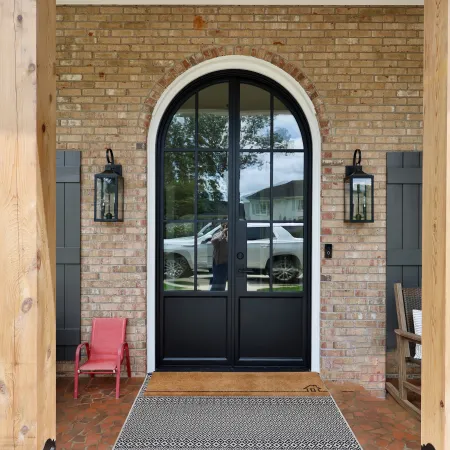 Arched double entry door with black iron and glass on a brick house