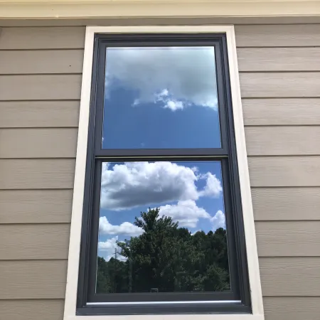 A black double hung window installed on a brown house by North Georgia Replacement Windows