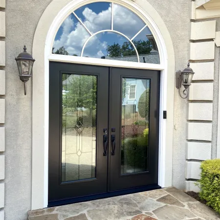 Black double front doors with decorative glass inserts and glass transom above the door