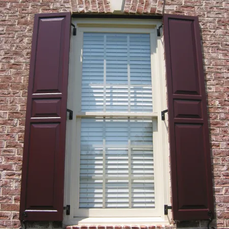 Red raised panel shutters on a brick house
