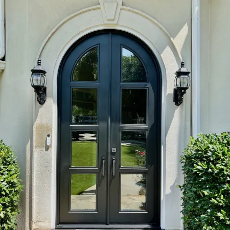 Black arched front doors installed in an arched opening on the home