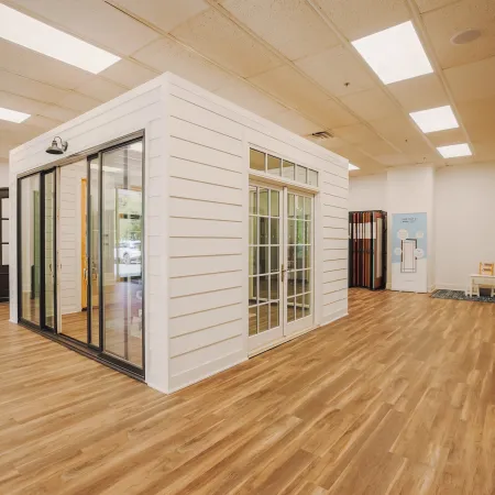 Modern showroom with hardwood floors featuring white siding room with glass sliding and French doors.