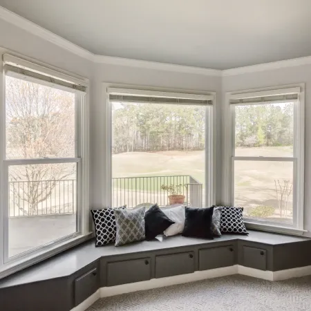 a room with a bay window with built-in seating and pillows