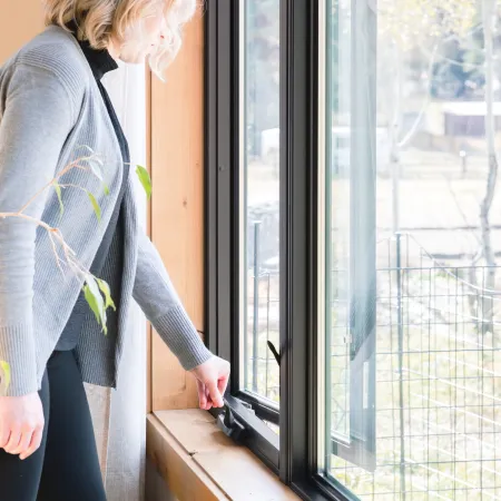 Infinity casement window with matte black finish being opened by a woman
