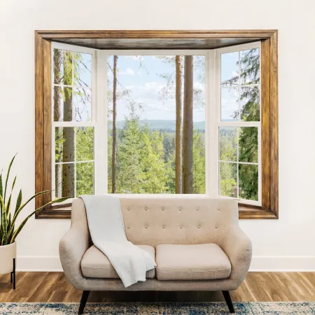a white chair in front of a bay window overlooking evergreen forest