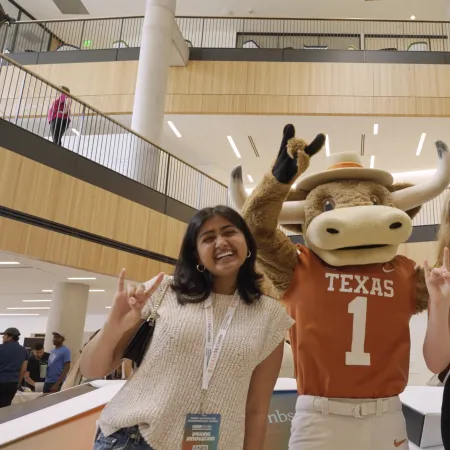 a couple of women posing with a mascot