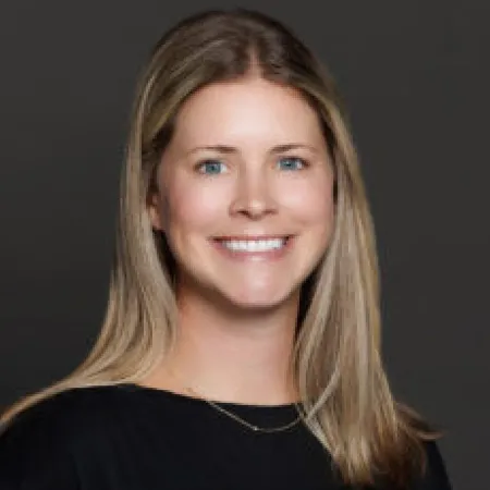 Portrait of a smiling woman with long blonde hair against a dark gray background
