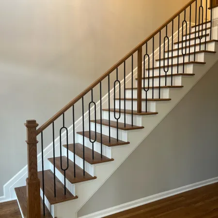 Wooden staircase with white risers and black metal railing in a modern home interior.