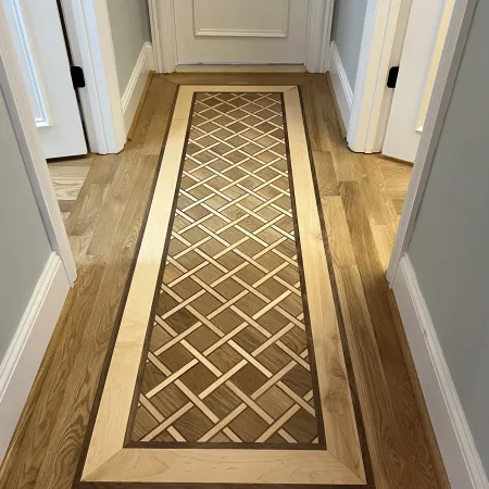 Intricate wooden floor inlay with geometric basketweave pattern framed by light and dark wood in a hallway.