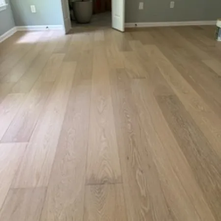 Light wood flooring in an empty room with gray walls and open double doors leading to another room.