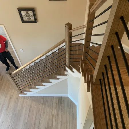 Top view of modern wooden staircase with metal railings and light hardwood flooring in a residential interior.