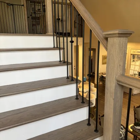 Modern wooden staircase with white risers and black metal balusters in a stylish home interior.