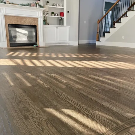 Sunlight casting striped shadows on polished hardwood floors in a living room with fireplace and staircase.