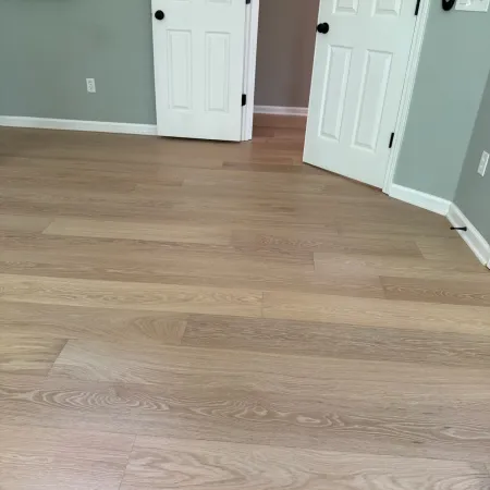 Room with light wood flooring, gray walls, white trim, and two white doors, one partially open.