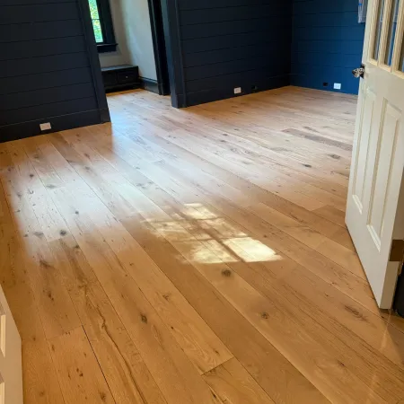 Spacious room with natural light on polished wooden plank flooring and dark navy walls.