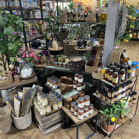 Interior of a shop showcasing jars of sauces, candles, wooden utensils, plants, and decorative baskets.