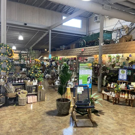 Interior of a spacious garden and gift store with plants, wreaths, garden products, and decorative items.