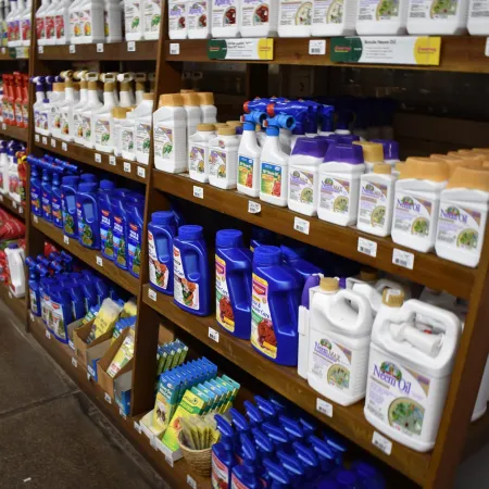 Store shelves stocked with various bottles of gardening and plant care products in white and blue packaging.