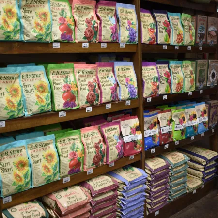 Shelves stocked with colorful bags of E.B. Stone Organics plant and flower food in a garden store.