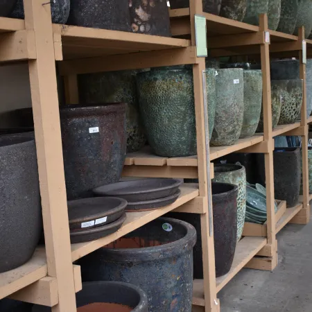 Shelves filled with various large textured ceramic and stone plant pots in different colors and sizes.