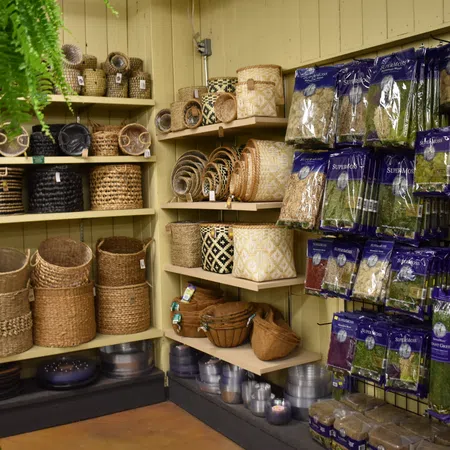 Store display of woven baskets and assorted dried herbs in purple packaging on wooden shelves and racks.