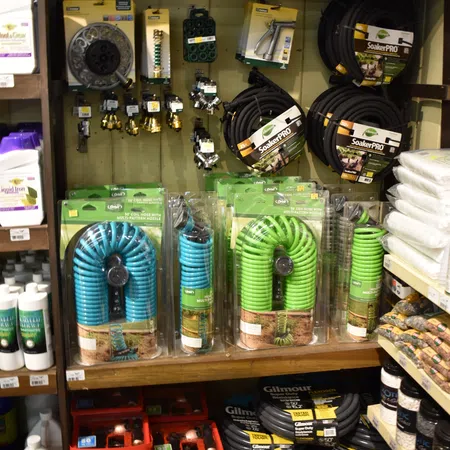 Garden hoses, sprayers, connectors, and watering accessories displayed on shelves in a store.
