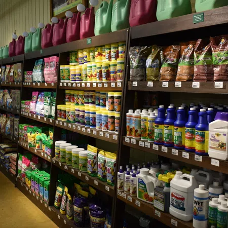 Store aisle with shelves filled with gardening supplies including fertilizers, plant food, and garden chemicals.