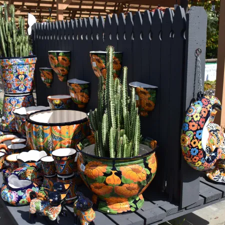 Colorful hand-painted ceramic pots and figurines with floral and bird designs displayed outdoors.