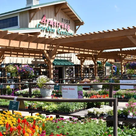 Armstrong Garden Center greenhouse with colorful flowers and plants under a wooden pergola on a sunny day