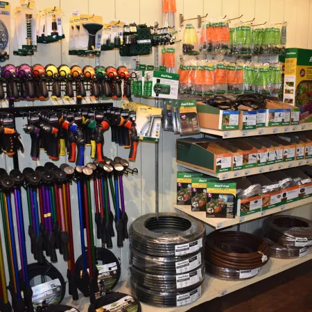 Garden irrigation tools and supplies including hoses, spray nozzles, and connectors displayed in a hardware store.