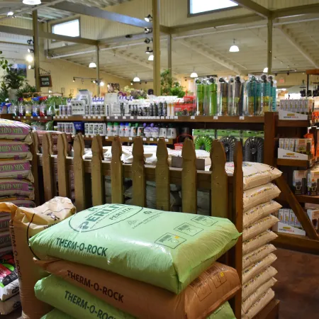 Indoor gardening store with bags of soil, fertilizer, and shelves stocked with plant care products under bright lights.