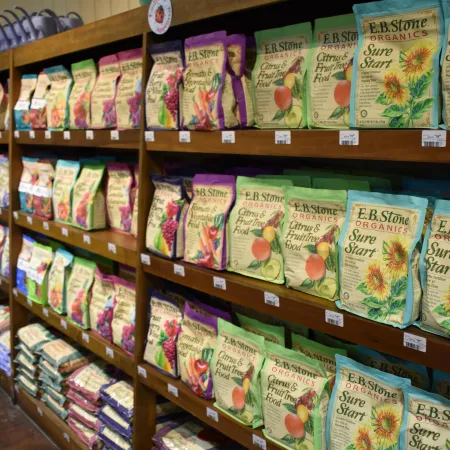 Shelves stocked with colorful E.B. Stone Organics gardening products including Sure Start and Citrus & Fruit Tree Food.