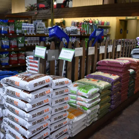 Stacks of various gardening soil and fertilizer bags displayed in a garden supply store aisle.