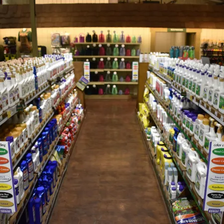 Store aisle with shelves stocked with garden chemicals including weed control and insect repellents.