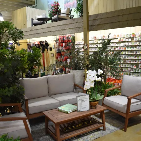 Cozy indoor garden store seating area with wooden furniture, plants, and seed packets displayed on the wall.