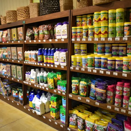 Shelves stocked with colorful gardening supplies including fertilizers, soil, and plant food in a garden store.